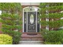 Elegant front entry with a black door, brick surround, and decorative glass panels at 1064 Saint James Xing, Brookhaven, GA 30319