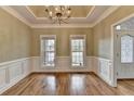 Dining room with hardwood floors, a tray ceiling, decorative trim, and views to the front yard at 3426 Olivia Grace Way, Dacula, GA 30019