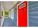 View of covered porch with a bright red front door with upper glass detailing and modern light fixture at 5200 Beechwood Forest Ct, Lithonia, GA 30038