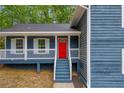 A close-up of the front of a two-story blue house, showing the front porch and a bright red front door at 5200 Beechwood Forest Ct, Lithonia, GA 30038