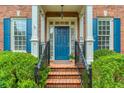 Close-up of a blue front door framed by white columns, brick steps, and manicured greenery at 3499 Paces Ferry Se Cir, Smyrna, GA 30080