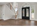 Grand foyer with hardwood floors, staircase with wood and iron railings, and stylish black double doors at 1066 Fairway Valley Dr, Woodstock, GA 30189