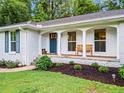 Inviting front porch with a blue door, decorative columns, and seating, enhancing the home's curb appeal at 4855 Kendall Ct, Atlanta, GA 30342