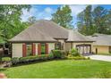 Lovely one-story home with red shutters, manicured lawn, and a two-car garage, nestled amongst mature trees at 2715 Woods Ridge Dr, Alpharetta, GA 30022