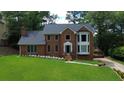 Charming two-story brick home with well-maintained lawn and mature trees, creating a serene setting at 10310 Amberside Ct, Roswell, GA 30076