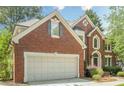 Charming brick two-story home featuring an attached garage and an arched entryway, complemented by mature landscaping at 425 Fieldstone Lndg, Alpharetta, GA 30005