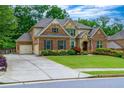 Traditional brick home with a well-manicured lawn, long driveway and attached two-car garage at 225 Sundance Dr, Woodstock, GA 30188