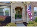 Covered front porch with brick detail and a decorative front door, trimmed with plants at 225 Sundance Dr, Woodstock, GA 30188