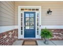 Close-up of a stylish front door with glass panels, brick accents and a potted plant at 1749 Grand Oaks Dr, Woodstock, GA 30188