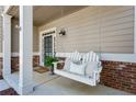 Cozy front porch with a swing, brick accents and neutral-colored siding at 1749 Grand Oaks Dr, Woodstock, GA 30188