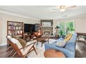 Cozy living room with a stone fireplace, ceiling fan, and large windows at 755 Waterbrook Ter, Roswell, GA 30076