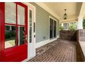 Inviting front porch featuring red brick, decorative brick columns, charming lighting, and a red front door at 775 A Harrison Se Pl, Atlanta, GA 30315