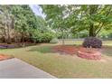 Spacious backyard with mature trees, a well-maintained lawn, and a brick planter at 627 New England Way, Lawrenceville, GA 30046