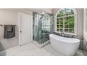 Spa-like bathroom featuring a soaking tub, a glass enclosed shower, and tiled floors at 2425 Hamptons Psge, Alpharetta, GA 30005