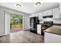 Bright kitchen with white cabinets, black appliances, and a sliding door to the deck at 2584 Shadowbrook Dr, Decatur, GA 30034