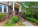 Charming front porch with brick steps, iron railing, and lush landscaping at 1393 Kings Park Nw Dr, Kennesaw, GA 30152