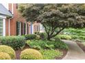 Well-manicured landscaping with mature tree leading to a classic brick home with blue front door at 680 Parkside Trl, Marietta, GA 30064