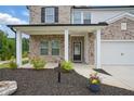 Inviting front entrance with a covered porch, featuring a brick facade, white columns, and landscaped flower beds at 4477 Bethany Manor Dr, Snellville, GA 30039