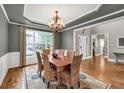 Formal dining room with wainscoting, tray ceiling, chandelier, and natural light at 1255 Hidden Creek Pt, Cumming, GA 30040