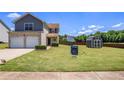 Exterior of house with spacious backyard, lush green lawn, storage shed, and sign in yard at 1932 Sawgrass Dr, Hampton, GA 30228