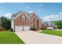 Expansive two-story brick home with a long driveway leading to a two car garage and landscaped front yard at 2372 Wilshire Way, Douglasville, GA 30135