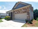 View of the two car garage with stone accenting and well manicured flower beds at 514 Creekshire Cir, Canton, GA 30115