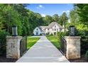 Impressive gated entrance with stone pillars and lanterns leading to the elegant home with perfectly manicured front lawn at 1191 W Conway Dr, Atlanta, GA 30327