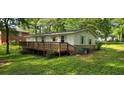 Backyard view featuring a wooden deck, green lawn, and mature trees providing shade at 50 Woodland St, Buford, GA 30518