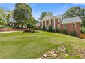 Spacious front yard with lush green grass and landscaping with a two-story brick home in the background at 828 Jami Ct, Lawrenceville, GA 30046