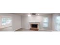 Open-concept living room featuring a brick fireplace, ceiling fan, and large windows at 2530 Flippen Rd, Stockbridge, GA 30281