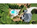 Expansive aerial view of a private backyard featuring a luxurious pool, surrounded by lush greenery, and an outdoor seating area at 102 Cavit Ct, Canton, GA 30114