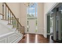 Bright foyer boasts hardwood floors, staircase with iron railing, and chandelier with large windows at 10660 Dunoon Dr, Alpharetta, GA 30022
