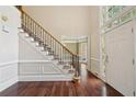 Staircase with wrought iron railing, hardwood floors, and front door with sidelight windows at 10660 Dunoon Dr, Alpharetta, GA 30022