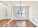 Open-concept dining room with wood floors, wainscoting and chandelier at 789 Clairidge Elm Sw Trl, Lawrenceville, GA 30046