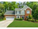 Two-story home with manicured lawn, brick accents, and attached garage surrounded by mature trees at 2865 Ivey Oaks Ln, Roswell, GA 30076