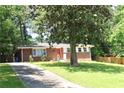 Brick home with a bright red front door nestled among mature trees and green lawn at 579 Kenridge Cir, Stone Mountain, GA 30083