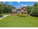 Expansive green lawn surrounds a classic two-story brick home with black shutters and well-maintained landscaping at 65 Millennial Ct, Lawrenceville, GA 30045