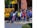Students exiting a yellow school bus near a brick building, showcasing accessibility to local schools at 5620 Moresby Ct, Alpharetta, GA 30022
