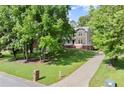 Two-story home featuring a long driveway, well-maintained lawn, and mature trees at 5150 Shadow Path Sw Ln, Lilburn, GA 30047