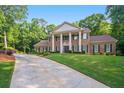 Brick home with large lawn, columned entryway, mature trees and a long driveway at 2080 Old Dominion Rd, Atlanta, GA 30350