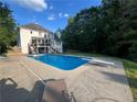 Backyard view showcases a sparkling blue in-ground pool and relaxing lounge area at 402 Hancock Ct, Woodstock, GA 30188