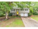 Traditional-style home with a bright yellow front door, two-car garage, and mature landscaping at 4171 Whispering Forest Sw Ct, Lilburn, GA 30047