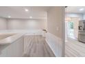 Open living room with light gray wood floors, wainscoting, and access to a modern kitchen with stainless steel appliances at 4171 Whispering Forest Sw Ct, Lilburn, GA 30047