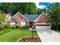Charming brick home with manicured lawn, mature trees, lamppost and attached two car garage, creating an inviting curb appeal at 4584 Brook Farms Dr, Duluth, GA 30096