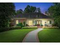 Charming home at dusk with a manicured lawn, lush greenery, and a welcoming walkway to the front door at 5945 W Andechs Smt, Johns Creek, GA 30097