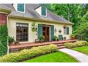 Charming home with a manicured lawn, lush greenery, and a welcoming brick-lined porch to the front door at 5945 W Andechs Smt, Johns Creek, GA 30097