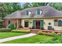 Charming home with a manicured lawn, lush greenery, and a welcoming brick-lined porch to the front door at 5945 W Andechs Smt, Johns Creek, GA 30097