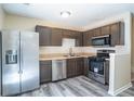 Modern kitchen with stainless steel appliances, dark cabinets, and stylish gray wood-look flooring at 6366 Jasper Ct, Tucker, GA 30084