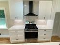Modern kitchen featuring stainless steel range and hood with sleek white cabinets and quartz countertops at 323 W Claiborne Ct, Marietta, GA 30066