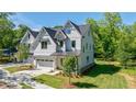 Beautiful two-story home featuring white siding, a landscaped lawn, and an attached garage, surrounded by trees at 136 Beutell St, Norcross, GA 30071